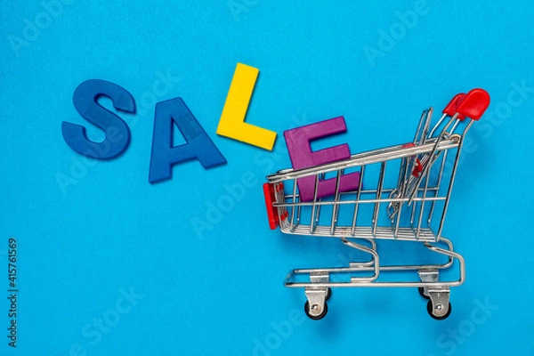 Obraz Empty shopping cart and inscription SALE on blue background