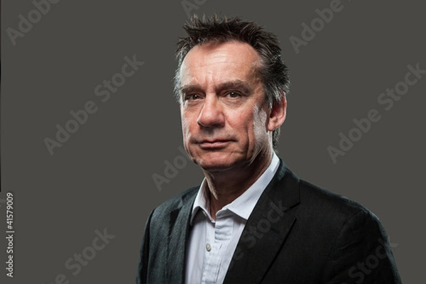 Fototapeta Portrait of Handsome Smiling Business Man in Suit on Grey