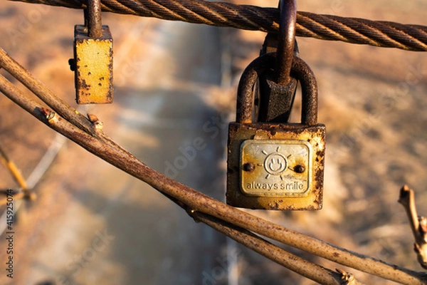 Fototapeta An old, rusty love lock displaying the words "Always Smile" hanging on steel wire from Haneul Sky Park in Seoul, South Korea. 