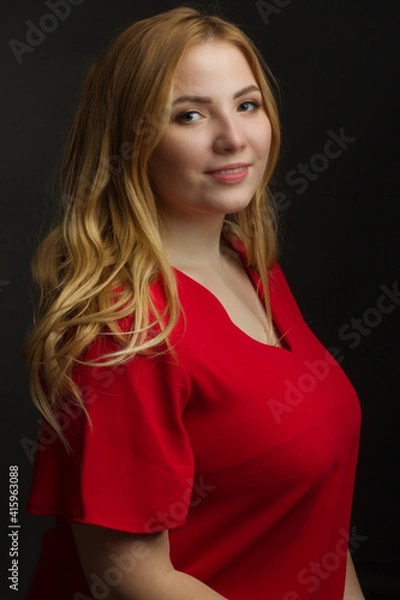 Fototapeta a blonde girl with an overweight plus size, a red overallposing on a dark Studio background