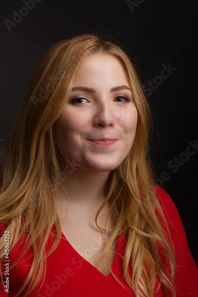 Fototapeta a blonde girl with an overweight plus size, a red overallposing on a dark Studio background