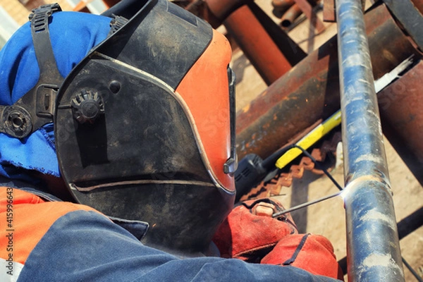 Fototapeta Welder in the mask and protective clothing is gaining increased cladding weld