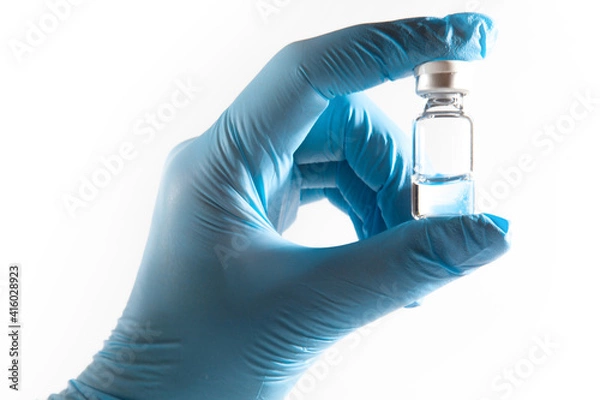 Obraz Medical theme: doctor's hand in a blue glove holding a vial of transparent liquid for injection