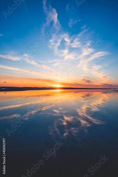 Obraz 波の水たまりに反射した夕日と空と雲