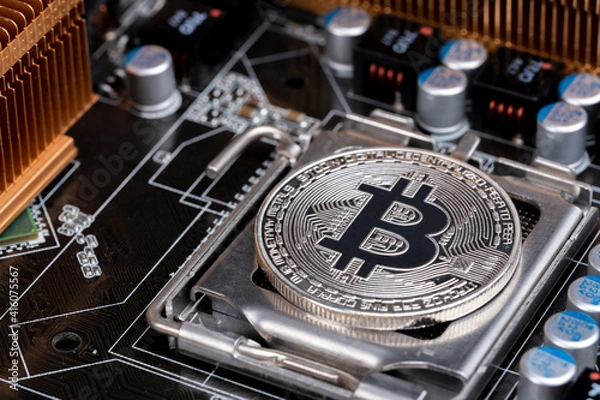 Fototapeta Crypto currency on global stock market and financial concept: Macro shooting of a silver bitcoin in a computer circuit main board. Economical elements and technology industry cooperation