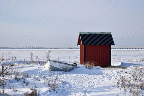 Obraz Old rowing boat by a red fishing shed