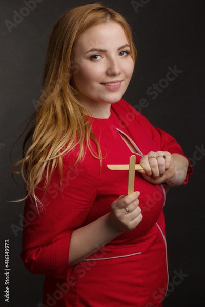 Fototapeta a blonde girl with an overweight plus size, a red overallposing on a dark Studio background