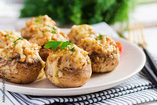 Fototapeta Baked mushrooms stuffed with chicken minced meat, cheese and herbs on light plate.