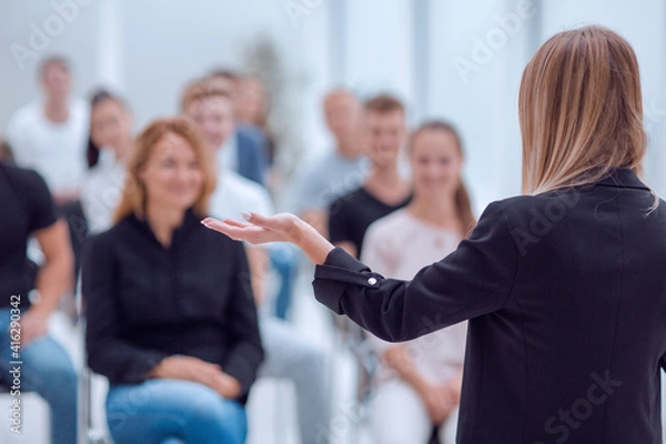 Obraz rear view. young woman doing a report for a group of young people