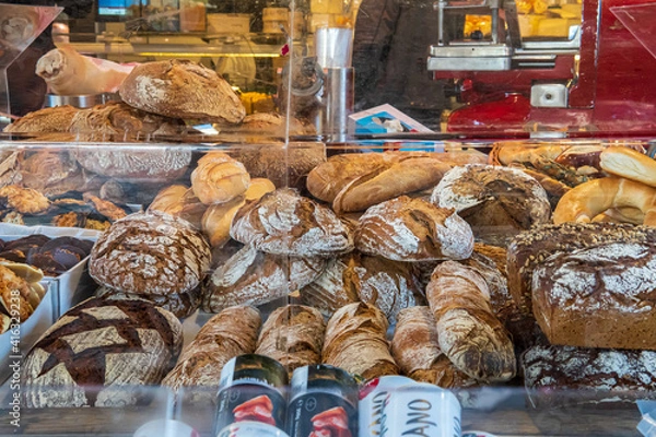 Obraz Freshly baked sourdough bread loaves for sale in a street market. Different kinds of artisan bread loaves displayed behind a glass window for shoppers. Market bakery at Naschmarkt, Vienna