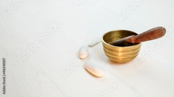 Fototapeta Singing bowl with pebbles on white wooden background with copy space