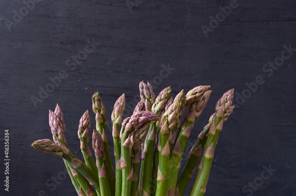 Fototapeta Fresh green asparagus on black wooden background with copy space. Close up view