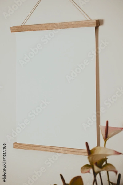 Fototapeta White frame on the wall with white paper and standing next to flower
