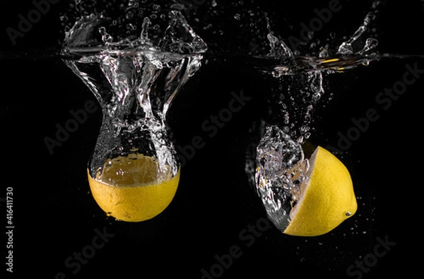 Obraz lemon falling into water black background
