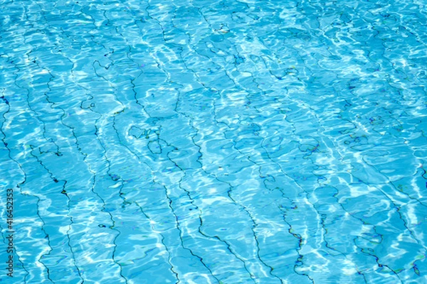 Fototapeta Jasnoniebieska woda falowaj z iskierkami i załamaniem fal wodnych. Streszczenie obrazu z powierzchni wody w basenie.