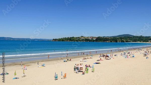 Fototapeta Panoramic view of the sandy beach of Miño in the Galicia region of Spain, with beach goers enjoying the summer weather.