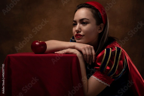 Obraz A girl in a princess costume with a red apple. A brunette. Fairy tale. Red lipstick.