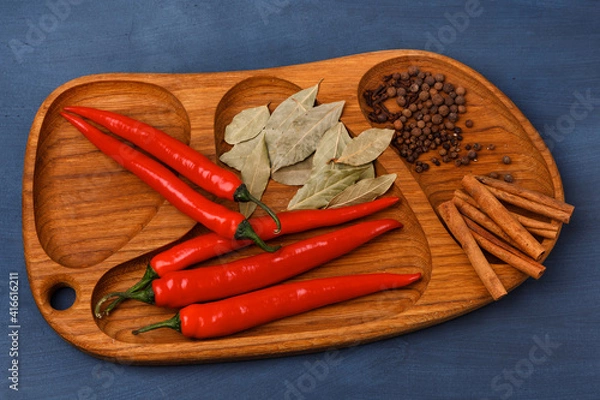 Fototapeta Red chili peppers with cinnamon rolls on a wooden surface