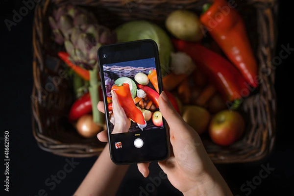 Fototapeta Teen blogger takes a photo on a smartphone for social networks. Diet, technology, health, food, cooking and people.