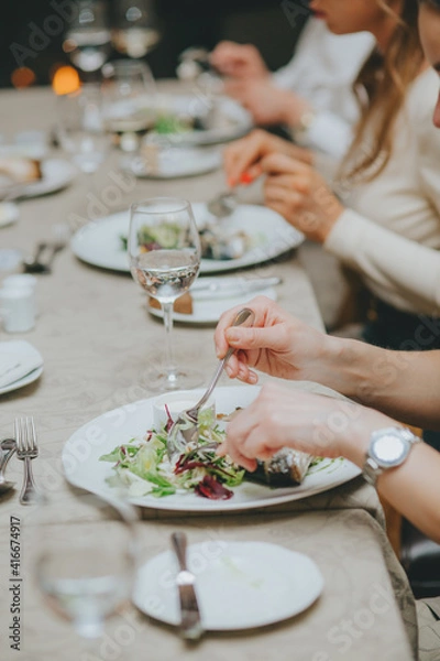 Fototapeta hands close up with etiquette cutlery. Eating a fish dish close up. Table etiquette.
