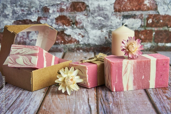 Fototapeta Three pieces of hand-scented organic soap, a gift box, and a candle.
