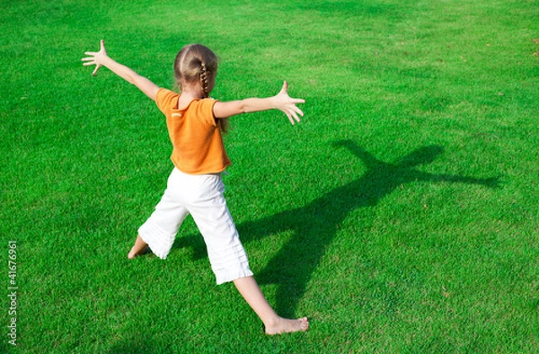 Obraz a girl standing on the grass  looking at his shadow