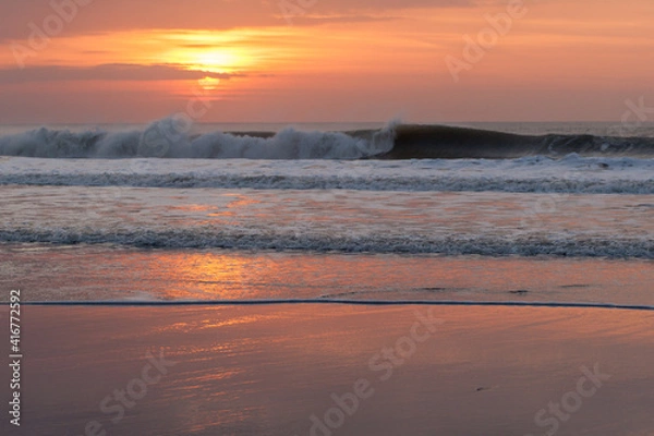 Obraz Waves crash against Welcombe Mouth beach in north Devon during sunset. The sunset is reflected in the sand.