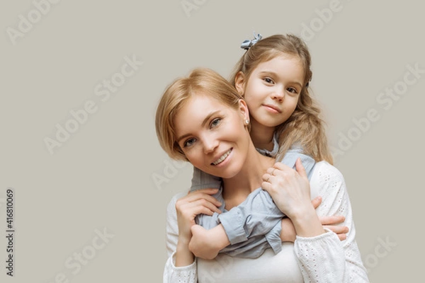 Fototapeta the concept of maternal love and care. mom and little daughter hug on gray background copy space happy family, parenthood