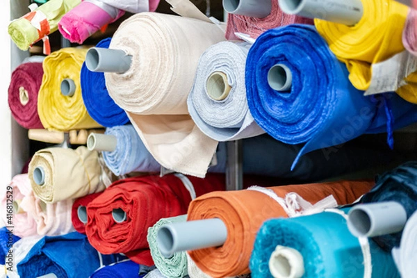 Fototapeta rolls of colored fabrics on a shelf in a warehouse