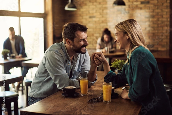Fototapeta Happy couple holding hands and talking in a cafe.