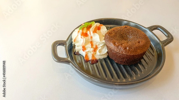 Fototapeta Chocolate cake with cream in the small pan on the white table