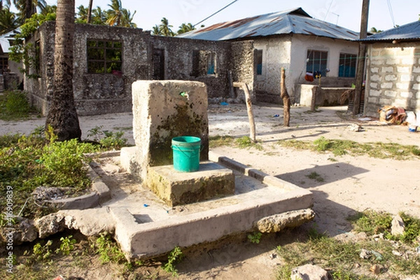 Fototapeta Drinking water supply, well in african village. Plastic container under the tap. Problem with access to the water in africa.