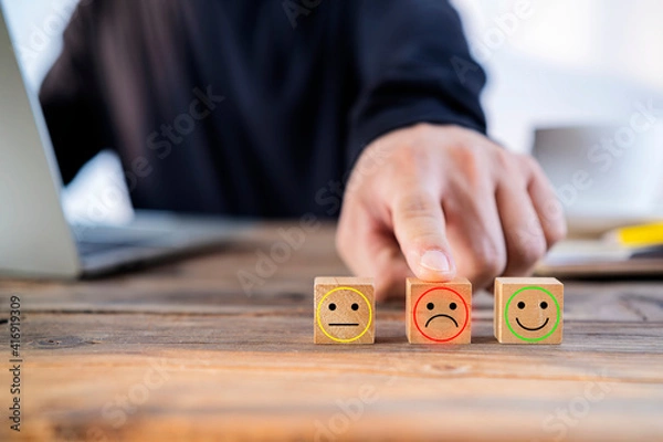 Fototapeta Close up customer hand choose sad face and smiley face icon on wood cube, Service rating, satisfaction concept