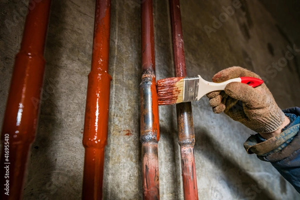 Fototapeta paint the pipe red with a brush and wear gloves