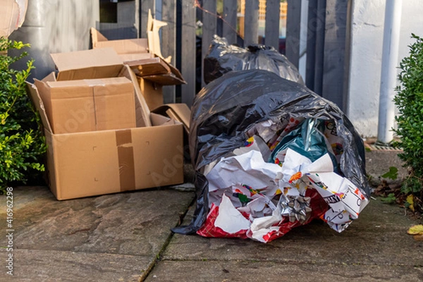 Fototapeta Christmas household waste consisting of boxes and wrapping paper at a trash can