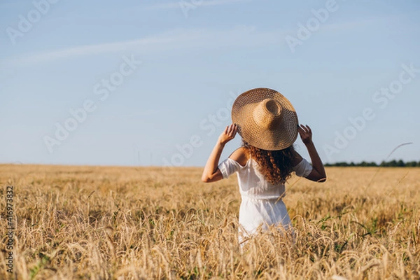 Obraz Girl with long curly hair poses in a wheat field