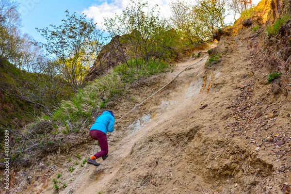 Fototapeta tourist tries to climb the mountain with a rope. Sakhalin Island Russia