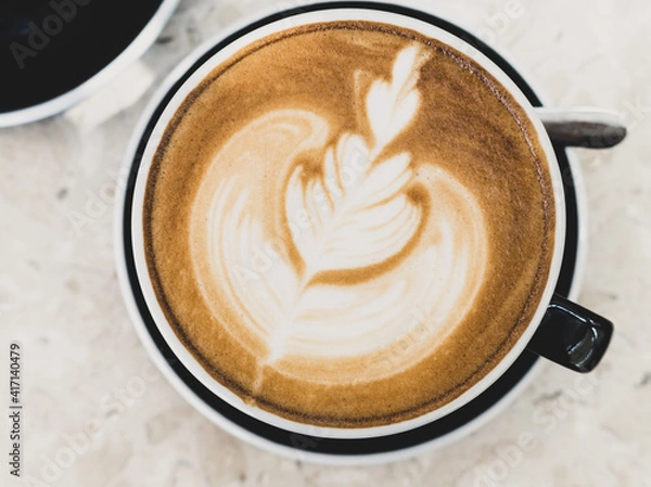 Obraz Top view of hot coffee latte foam of flower design art on beige marble table in cafe. Drink and beverage.