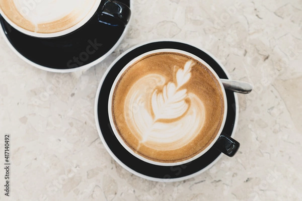 Obraz Top view of hot coffee latte foam of flower design art on beige marble table in cafe. Drink and beverage.
