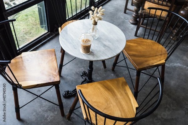 Obraz Iced coffee with straw and vase of decoration plant on the marble tale in cafe.