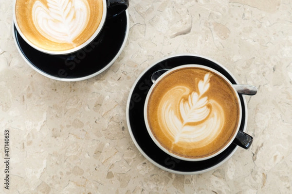 Obraz Top view of hot coffee latte foam of flower design art on beige marble table in cafe. Drink and beverage.