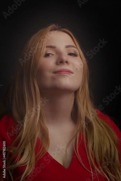 Fototapeta a blonde girl with an overweight plus size, a red overallposing on a dark Studio background