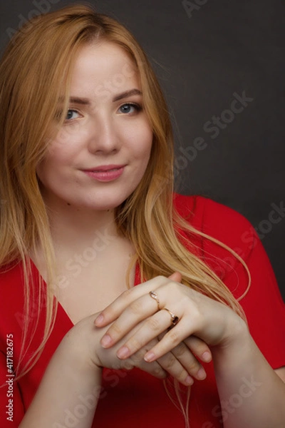 Fototapeta a blonde girl with an overweight plus size, a red overallposing on a dark Studio background