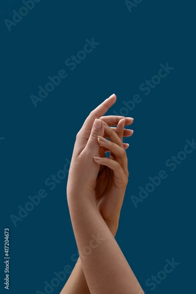 Fototapeta Close up of two female hands uniting with each other isolated on blue background