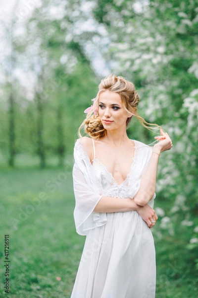 Obraz Portrait of a young woman in the spring in the park in a white boudoir dress