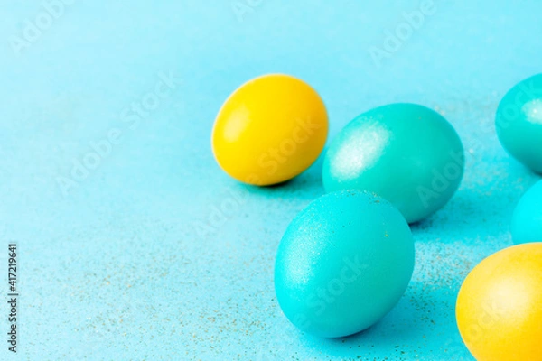 Fototapeta Traditionally painted Easter eggs on sparkling pastel azure background. Copy space.