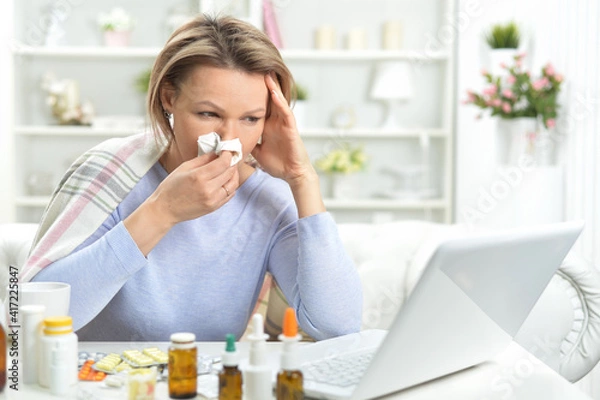 Obraz beautiful young woman with pills using laptop