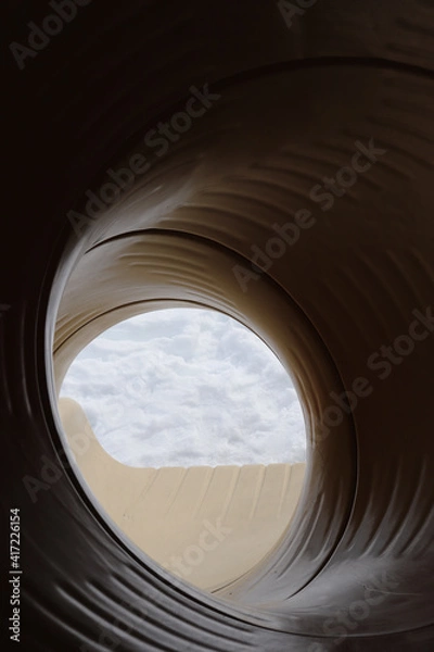 Fototapeta Yellow tunnel slide in the winter at a playground