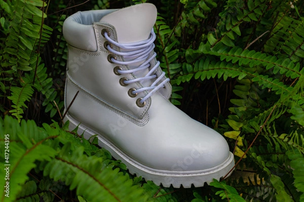Fototapeta White boot shoe with low platform sole in the foreground, surrounded by green grass