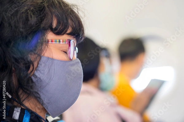 Obraz An Asian woman wearing a mask asleep on a passenger plane.
